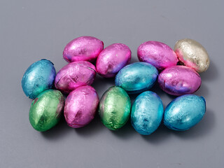 chocolate candies in foil in the form of Easter eggs on a gray background