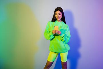 Photo of charming stunning young woman dressed green hoodie chatting modern gadget isolated neon color background