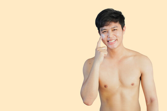 Close Up Young Asian Man Applying Sunscreen Uv-protection On Face And Smile While Thinking And Looking On Cream Background For Advertising Product Concept	