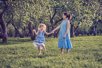 Naklejka na ściany i meble nature scene with family outdoor lifestyle. Mother and little daughter playing together in a park. Happy family concept. Happiness and harmony in family life.