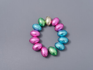chocolate candies in foil in the form of Easter eggs on a gray background