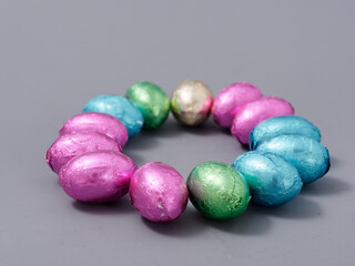 chocolate candies in foil in the form of Easter eggs on a gray background