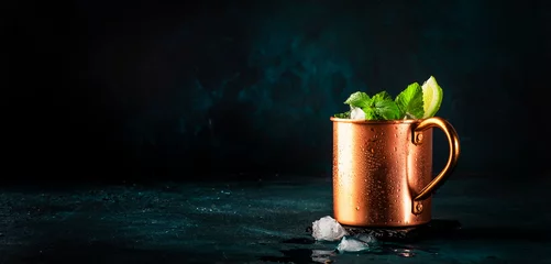 Foto auf Acrylglas Moscow mule alcoholic cocktail in copper mug with lime, ginger beer, vodka and mint. Blue table, copper bar tools © 5ph