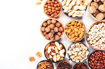 Nuts in bowls set. Cashews, hazelnuts, walnuts, pistachios etc. Healthy food snack mix on white table, top view