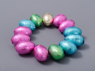 chocolate candies in foil in the form of Easter eggs on a gray background