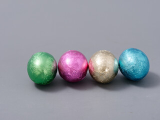 chocolate candies in foil in the form of Easter eggs on a gray background