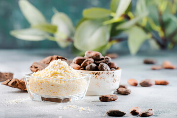 Organic cocoa butter bowl, beans, grated lump on gray table. Copy space