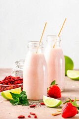 Healthy blended diet smoothie drink with strawberry and goji berries, chia seeds and lime. Glass bottles with eco fendley straws