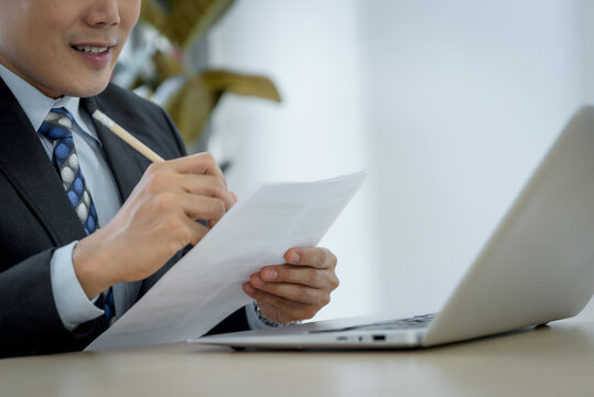 Handsome asina businessman making notes in office.