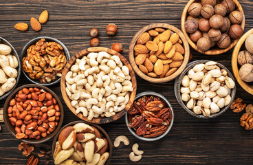 Nuts in bowls. Walnuts, pistachios, pecans, macadamia, almonds and other. Healthy food snacks mix on wooden background, top view