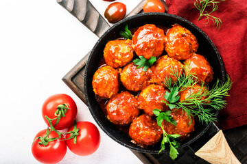 Meatballs with spicy tomato sauce in frying pan on white kitchen table. Top View