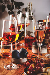 Pink rose wine glasses and bottles on table served for summer festive dinner party with different kinds of appetizers