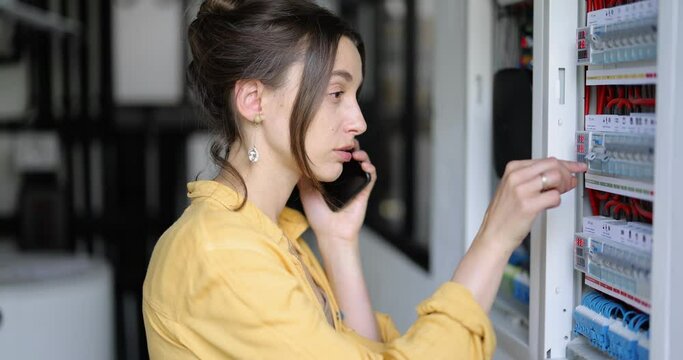 Confused woman having problems with electricity at home, speaks on the phone trying to solve the problem. Concept of female incompetence in home electricity