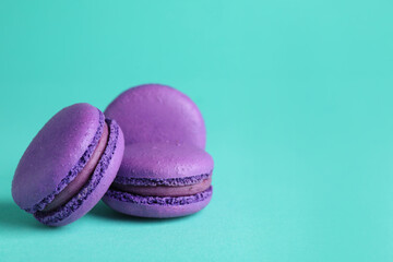 Delicious purple macarons on turquoise background. Space for text