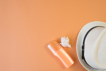 Top view of seashells, sunscreen and hats with copyspace. Summer concept. Orange background. flat lay