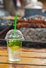 Green mojito on a grill background. Cocktail with lime and mint. The concept of summer outdoor recreation and festivals.