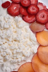 Fruit, berry dessert on a plate with healthy cottage cheese, close-up, top view