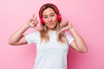 Young australian woman listening music isolated on pink background feels proud and self confident,...