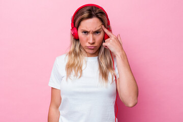 Young australian woman listening music isolated on pink background showing a disappointment gesture with forefinger.