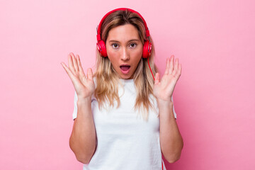 Young australian woman listening music isolated on pink background surprised and shocked.