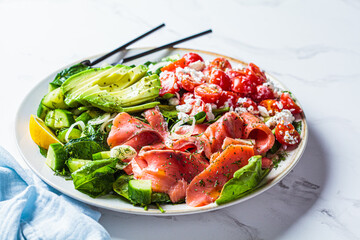 Fish salad with avocado, tomato, cucumber and onion. Keto diet recipe, Mediterranean cuisine.
