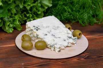 Piece of French Roquefort cheese with olives and fresh herbs
