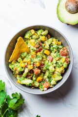 Avocado dip guacamole with grilled corn in gray bowl, top view. Vegan food concept, Mexican cuisine.
