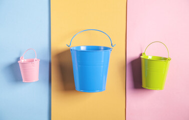 Pink, blue, green bucket on the color paper background.