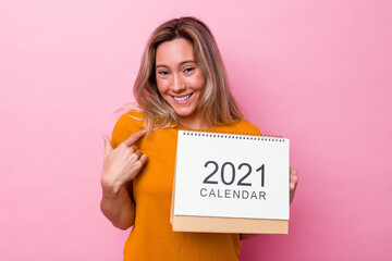 Young australian woman holding a calendar isolated on pink background pointing with finger at you as if inviting come closer.
