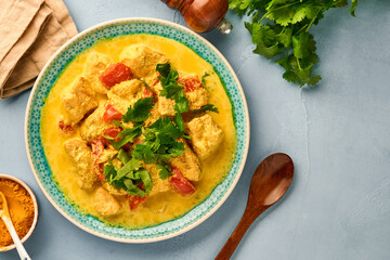 Chicken tikka masala. Traditional of indian cuisine curry and ingredients on dark background. Curry, lime, ginger, cilantro, chili, rice, herbs and spices. Top view with copy space.