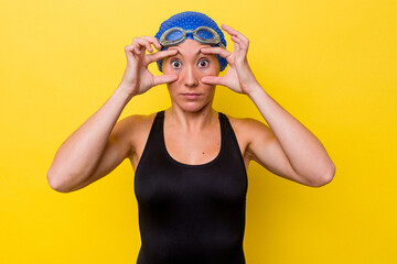 Young australian swimmer woman isolated on yellow background keeping eyes opened to find a success opportunity.