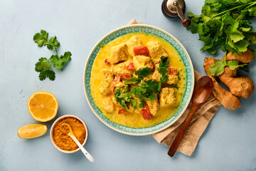 Chicken tikka masala. Traditional of indian cuisine curry and ingredients on dark background. Curry, lime, ginger, cilantro, chili, rice, herbs and spices. Top view with copy space.