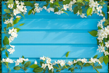 Obraz na płótnie Canvas Beautiful summer apple tree flowers on a blue wooden background. Romantic floral or Valentine’s Day background. For card design and wedding. Congratulations or invitations with copy space