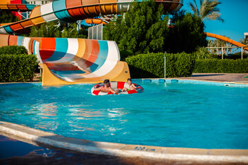 Action shot of father and son at the water park. Have fun together in the aqua park.