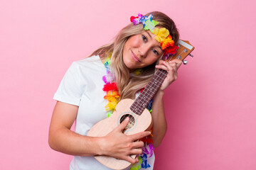 Young hawaiian woman playing a ukulele isolated on pink background