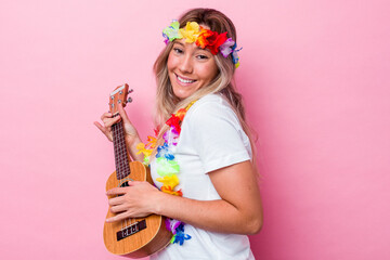Young hawaiian woman playing a ukulele isolated on pink background