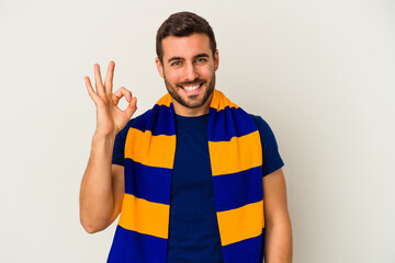 Young caucasian fan of a soccer team isolated on white background cheerful and confident showing ok gesture.