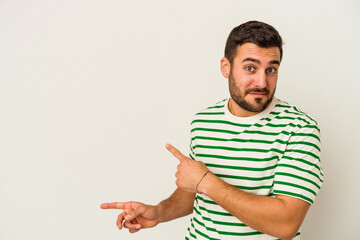 Young caucasian man isolated on white background shocked pointing with index fingers to a copy space.