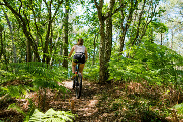 pretty yellow athletic woman mountain biking in the forest