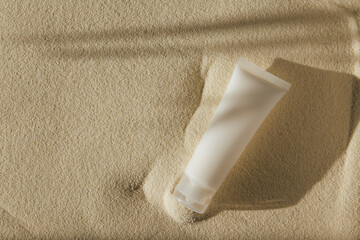 a bottle of cream on a sand background 