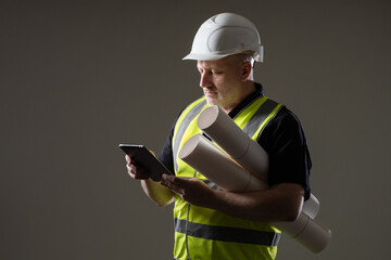 Builder worker with tablet in his hands. Adult builder worker on dark background. Man builder...