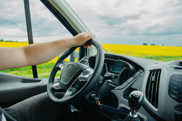 concept of a truck driver, driver's hands on the steering wheel on a sunny day in summer.
