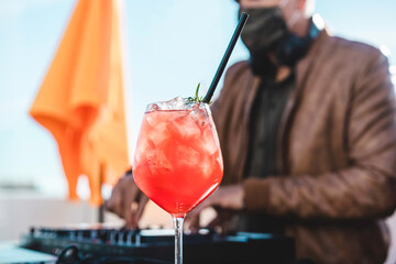 Close up of a special cocktail at beach party - Dj playing music at cocktail bar outdoor wearing...