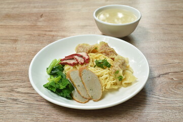 Chinese egg yellow noodles with barbecue pork and dumpling on plate with soup cup