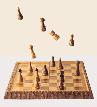 Chess board with flying pieces on beige and white background.