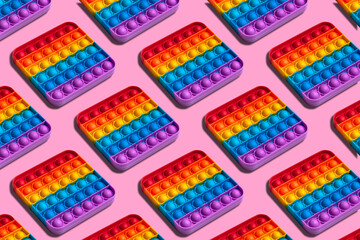 Rainbow square shape isometric pattern of silicon toy for kids. Pop it fidget toy on pastel background. Simple dimple toy on pink pastel background.  - obrazy, fototapety, plakaty
