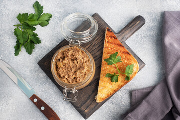 Homemade chicken liver pate in a glass jar on a gray concrete table.
