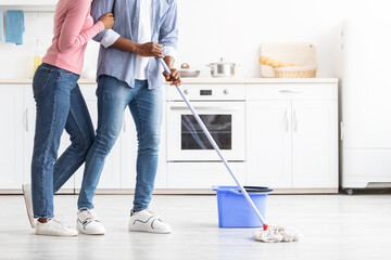 Cropped of black couple mopping floor in kitchen