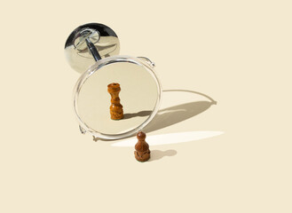 From pawn to queen in the mirror. Creative arrangement of chess pieces on beige background.