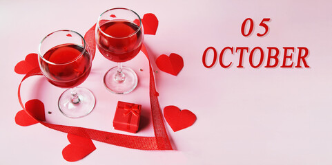 calendar date on light background with two glasses of red wine, red gift box and red hearts with copy space. October 5 is the fifth day of the month
